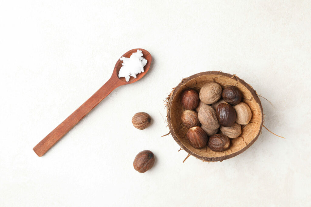 Shenüsse in einer Holzschale, daneben ein Löffel mit Sheabutter