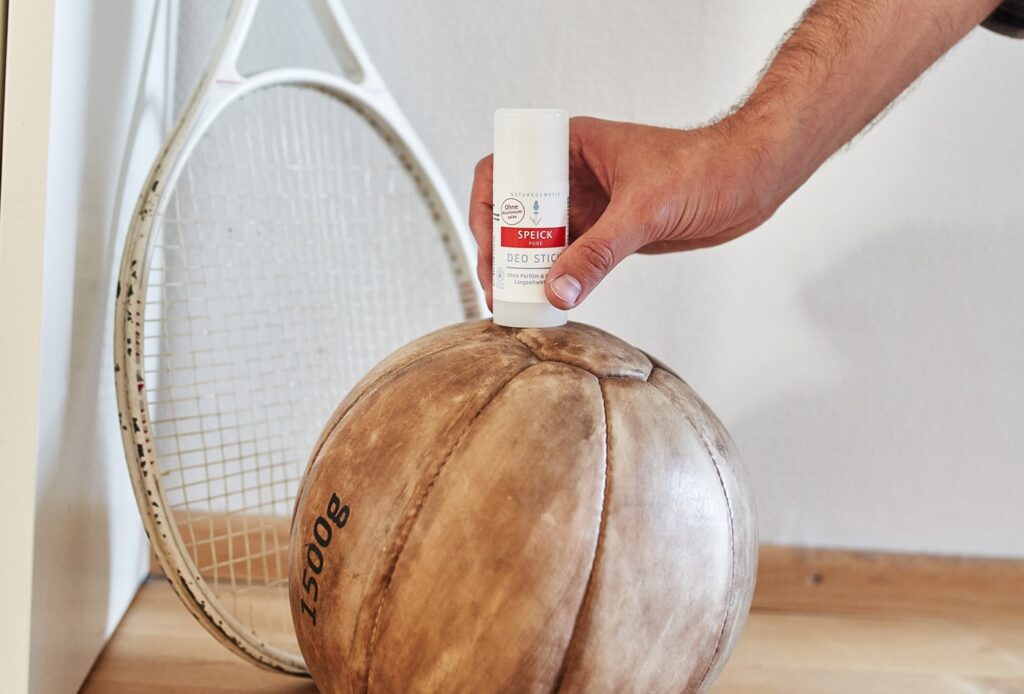 Der Speick Pure Deo Stick mit Männerhand auf einem alten Medizinball
